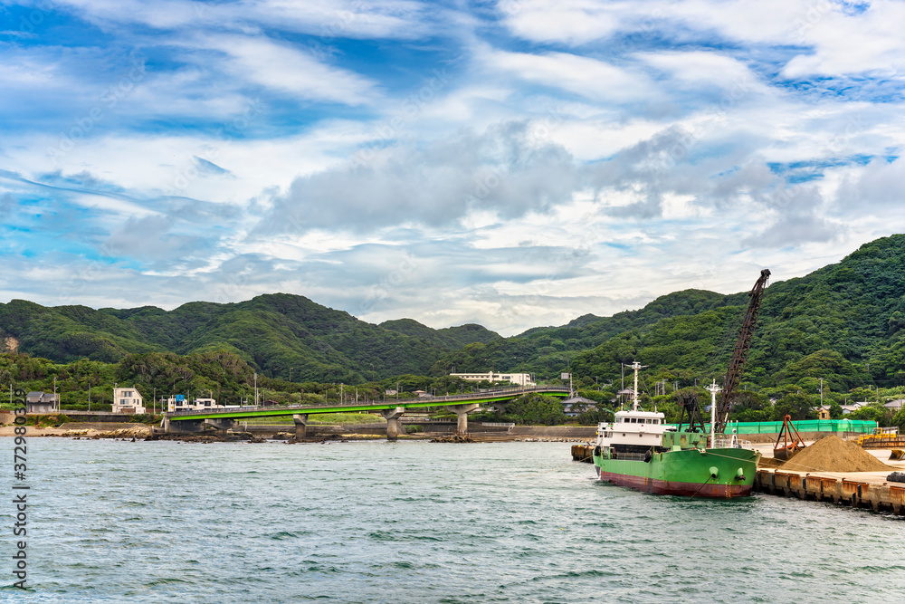 Coast of the Bōsō Peninsula with the loop ramp of the Futtsu Kanaya Interchange along the Uraga Channel and a sand carrier ship mooring in front of the Mount Nokogiri.