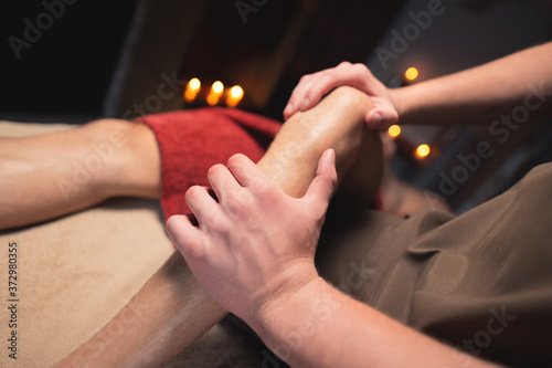 Male masseur doing sports massage of the lower leg to the athlete in the massage spa salon