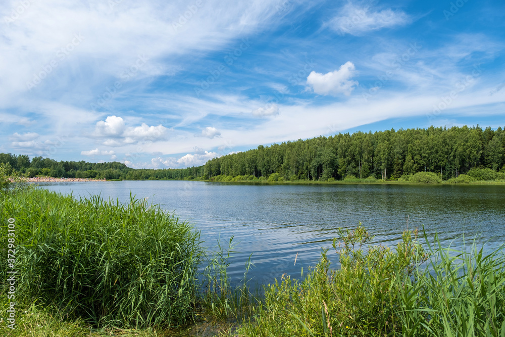 A large lake near the village of Khramtsovo and a sandy beach on a summer day.