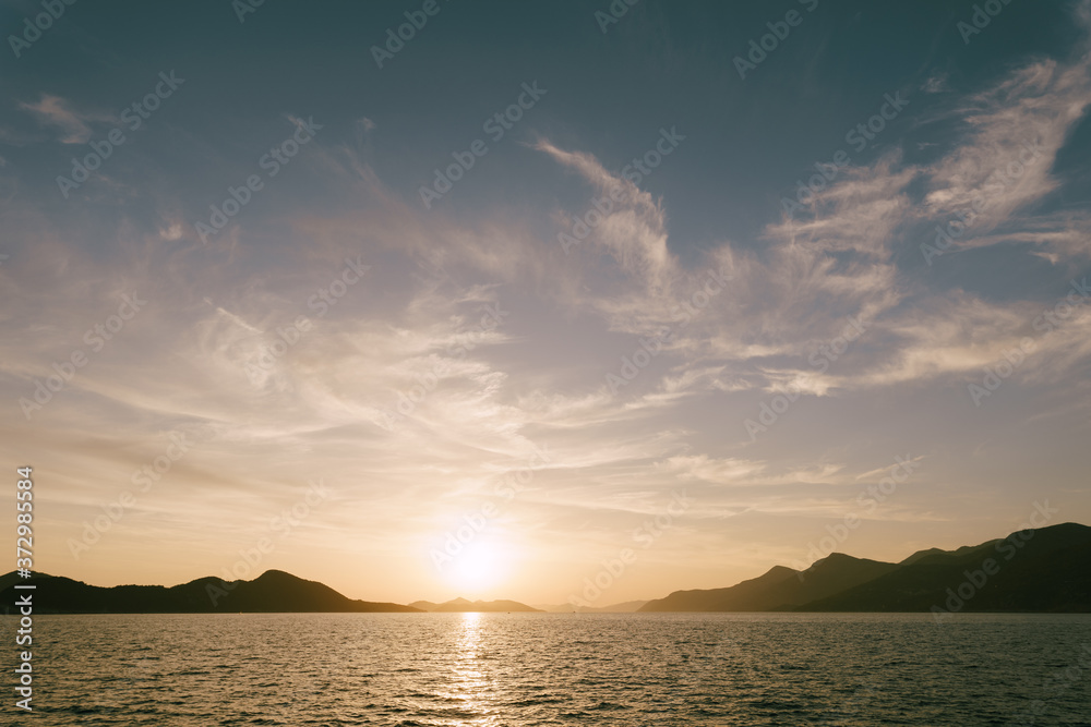 A bright sunset in the sea above the mountains.