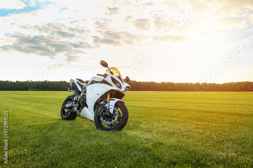 white sport motorcycle on grass at sunset