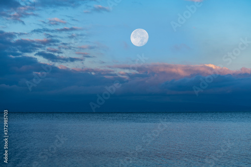 Beautiful sunrise on the lake with full moon.