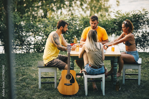 Two couples sit outside in nature, enjoying themselves, eating fast food, drinking beer and smiles photo