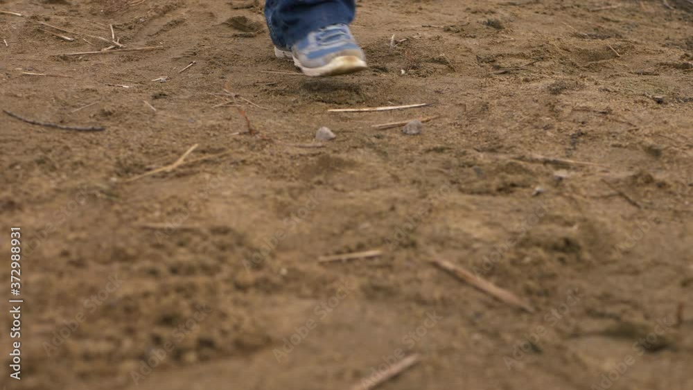 Solitary person feet walking across golden sand Solitary person feet walking across golden sand