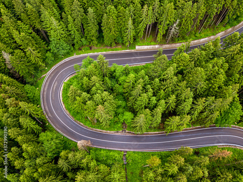 Winding road through the forest, from high mountain pass, aerial view