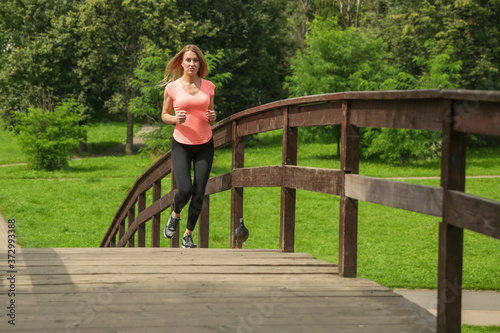 young sport woman running across the bridge in the park