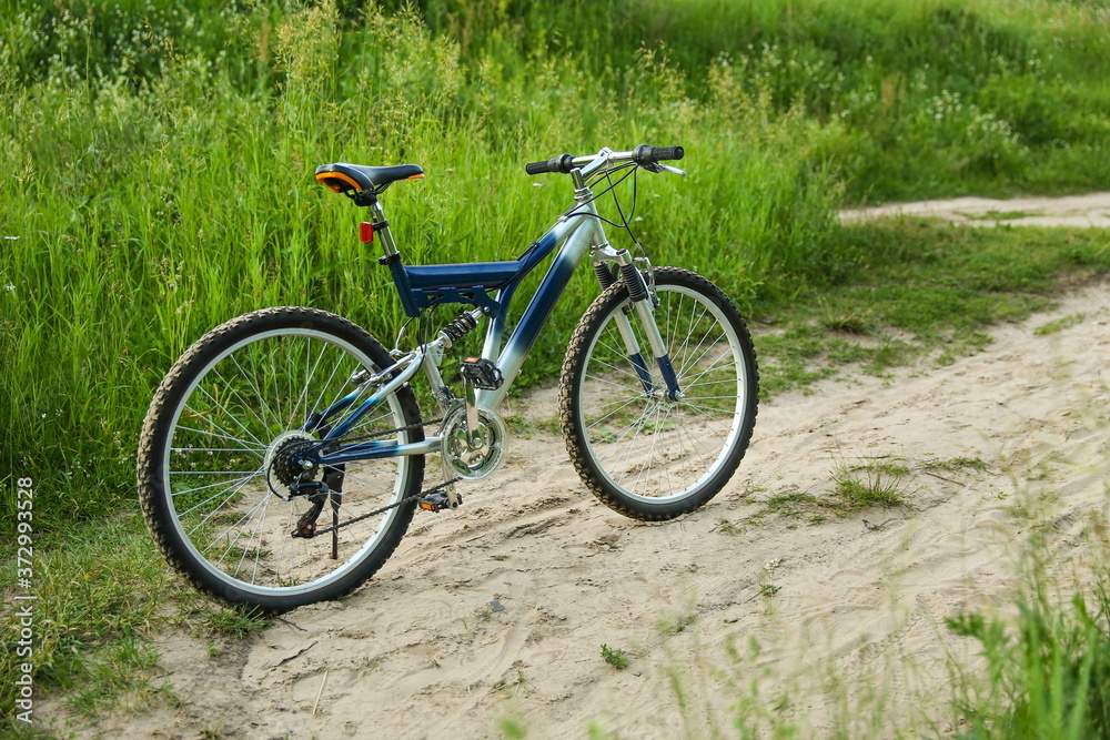 beautiful mountain bicycle is on sand road on green nature background at sunset beautiful mountain bicycle is on sand road on green nature background at sunset