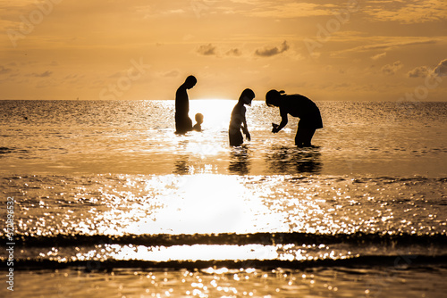 A silhouette of a child in the morning sea while the sea is calm and quiet.