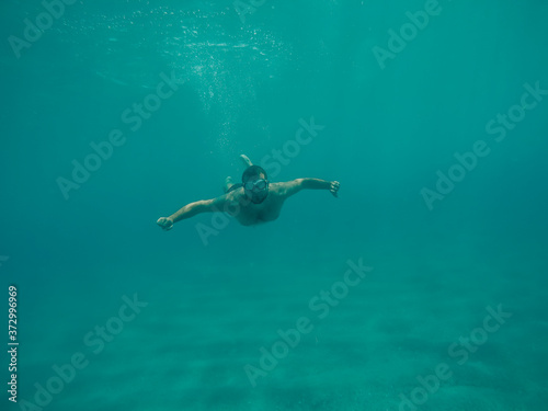 Young boy diving under the sea.