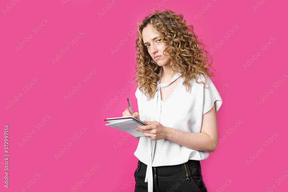 Charming woman makes entries in the diary and looks into the camera Charming woman makes entries in the diary and looks into the camera