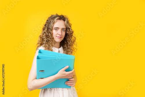 A young woman holds folders with documents in her hands.