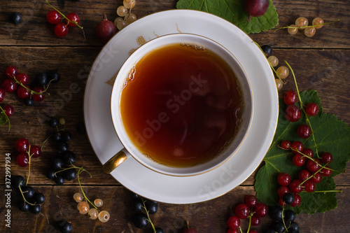 Vintage cup of tea with gold decoration on the old wooden table on which berries lie