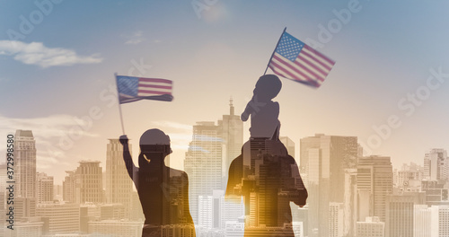 Patriotic man, woman, and child waving American flags in the air on city sunrise background 