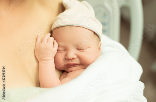 Newborn adorable baby girl resting sleeping in mothers arms 
