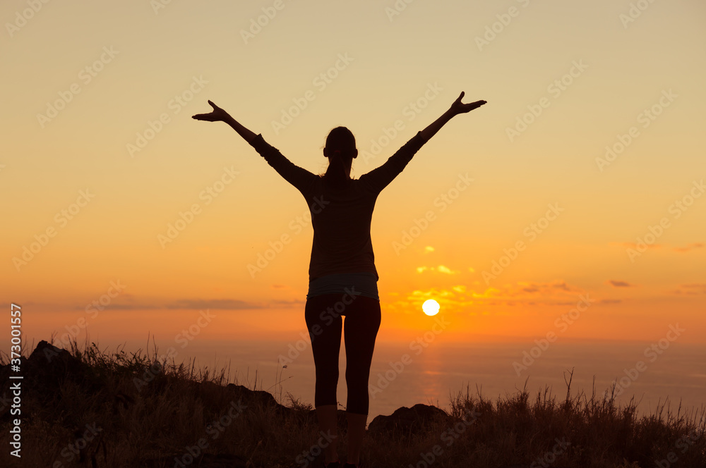 silhouette of a woman in the sunset raising her arms up feeling inspired 