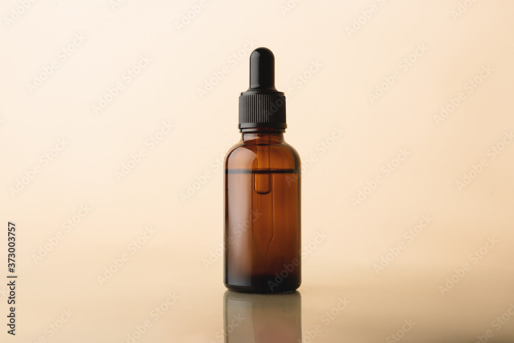 Serum glass bottle with pipette on the beige reflective background. Natural Organic Spa Cosmetic concept. Front view.