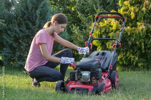 Fotografie Woman checking lawn mower oil