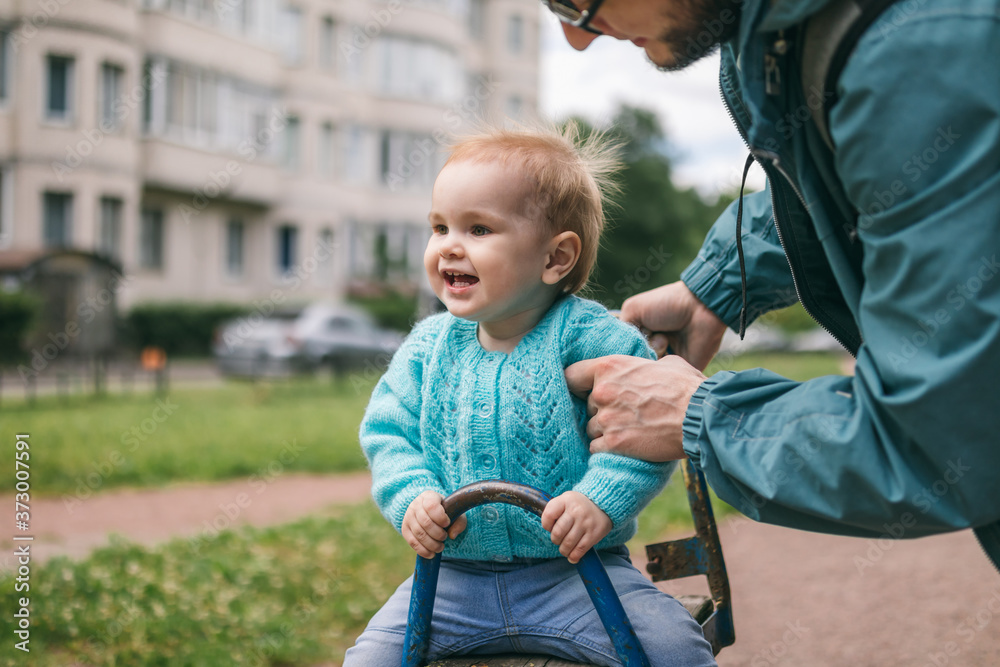 Fototapeta premium Child swinging on the seesaw walks with his father