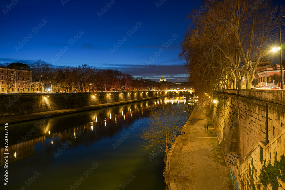 Foto noturna de longa exposição da ponte iluminada sobre o rio na cidade de Roma.