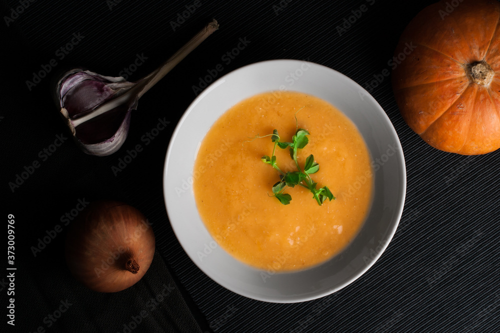 Pumpkin soup with ingredients on the dark background. Pumpkin soup with ingredients on the dark background.