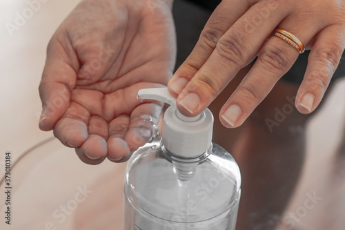 Hand sanitizer woman applying sanitizing gel liquid rubbing hands clean personal hygiene coronavirus pervention at home. Sanitiser bottle. photo