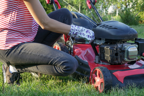 Obraz na plátně Woman checking lawn mower oil