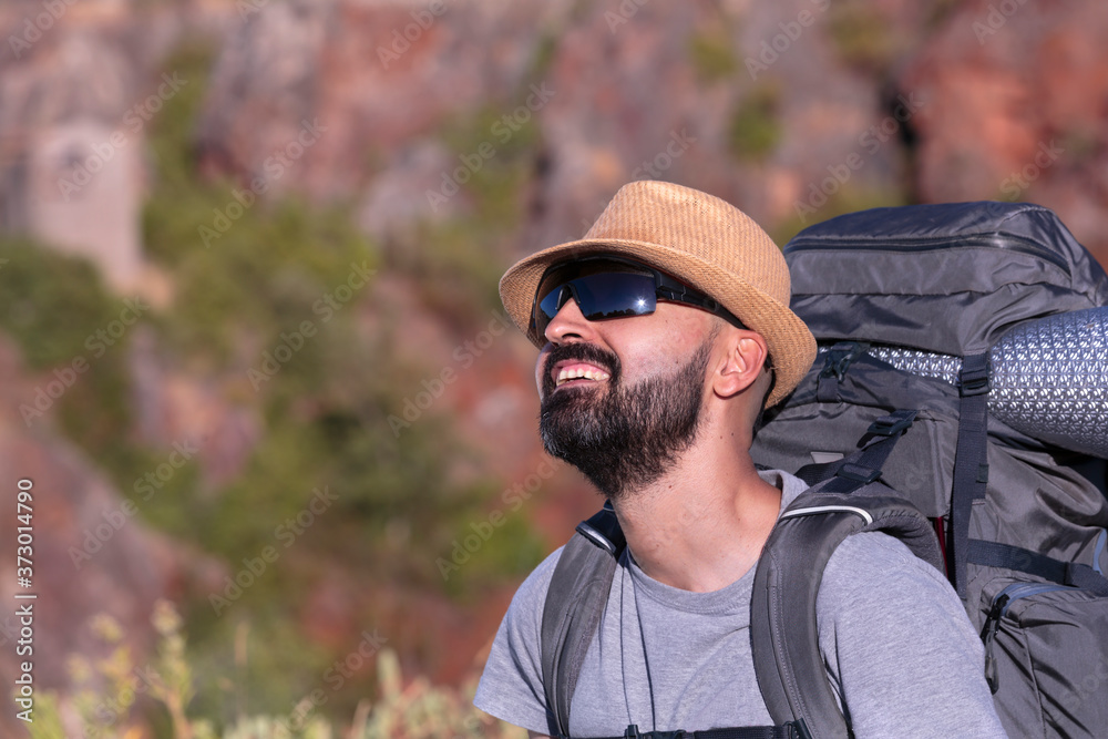 Hispanic male trekker with sunglasses smiling and admiring nature