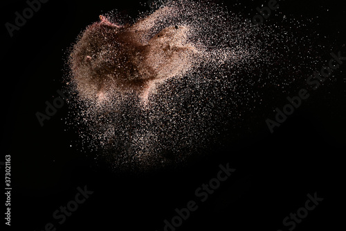 Gold sand explosion isolated on black background. Abstract sand cloud.