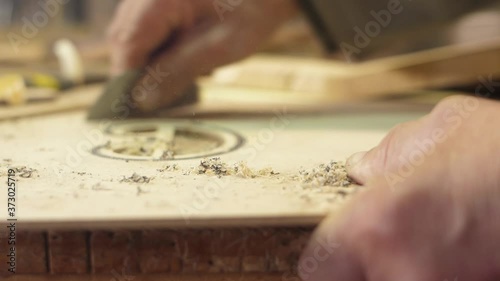 Craftsman artisan file wood with sharp knife to make guitar 