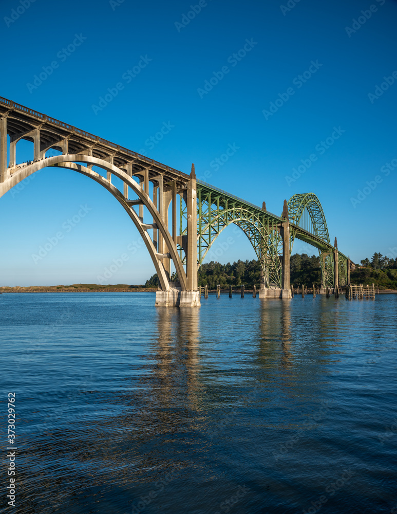 A side profile view of the Yaquina Bay Bridge  taken at sunrise during low tide in Newport Oregon in vertical orientation