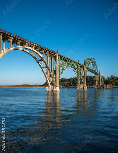 A side profile view of the Yaquina Bay Bridge  taken at sunrise during low tide in Newport Oregon in vertical orientation © Jsmcpheeters