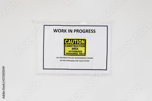 Under construction sign pasted on a boarded up area cautioning the public of maintenance and upgrading works in progress at a section of a building with only authorized personnel allowed entry.