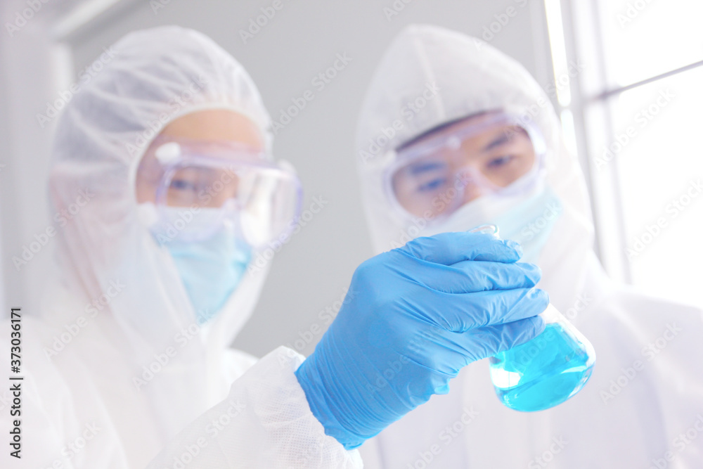 doctors in virus protective suit working in lab looking the example in glass bottle doctors in virus protective suit working in lab looking the example in glass bottle