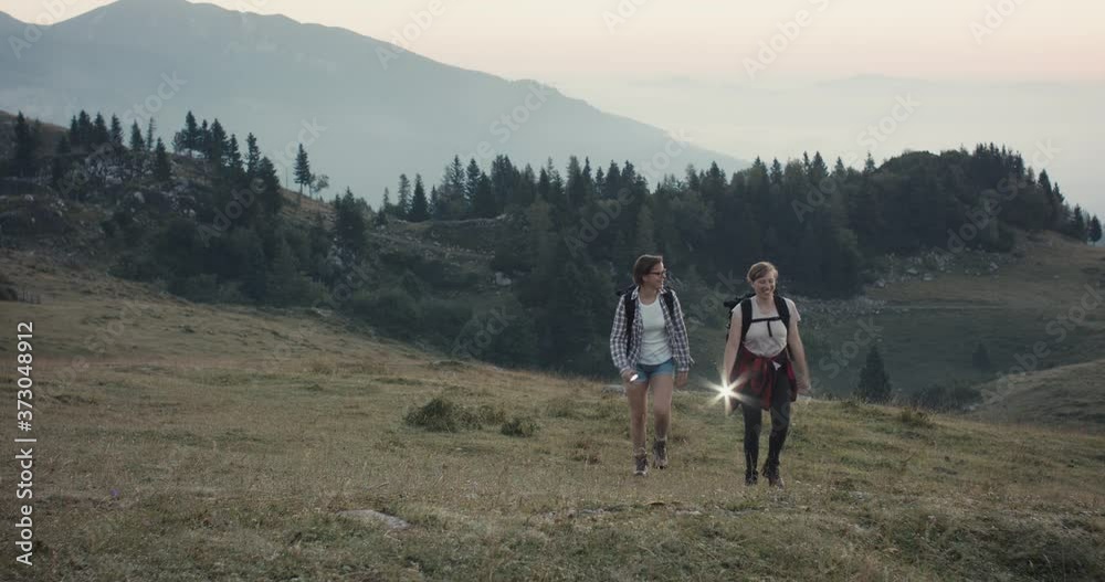 Friends on a hike in the mountains hiking together on a trail wear backpack with flashlight light in early fall or autumn morning dusk walk by pan real time Friends on a hike in the mountains hiking together on a trail wear backpack with flashlight light in early fall or autumn morning dusk walk by pan real time