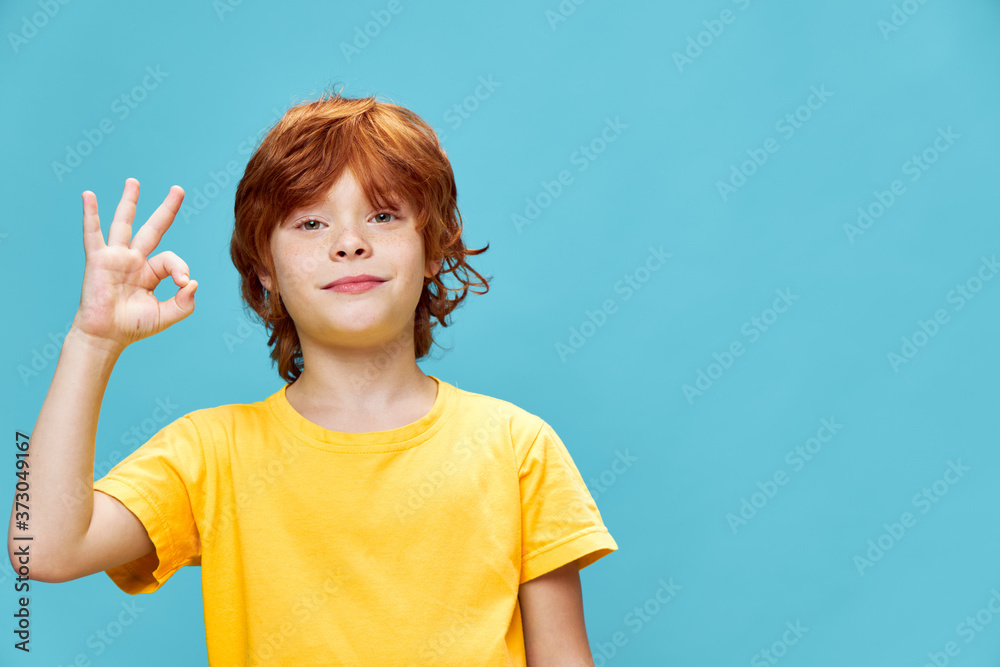 The red-haired boy in a yellow T-shirt connected the forefinger and thumb i The red-haired boy in a yellow T-shirt connected the forefinger and thumb i