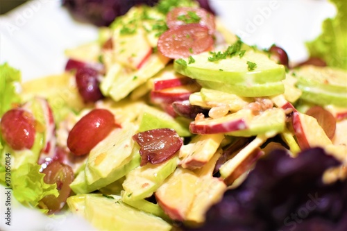 A healthy serving of salad with fresh lettuce, cucumber, grapes, and olive oil dressing