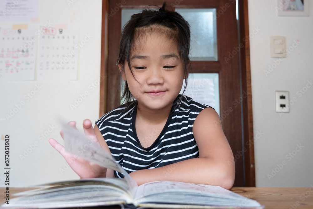 asian little girl reading a book in a room asian little girl reading a book in a room