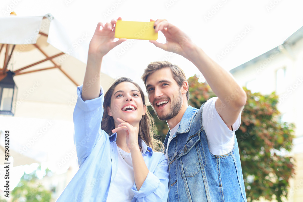 Beautiful lovely young couple walking at the city streets, hugging while taking a selfie. Beautiful lovely young couple walking at the city streets, hugging while taking a selfie.