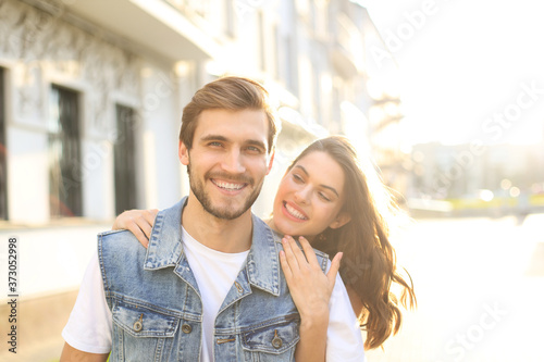 Beautiful young couple in love walking outdoors at the city street, hugging.
