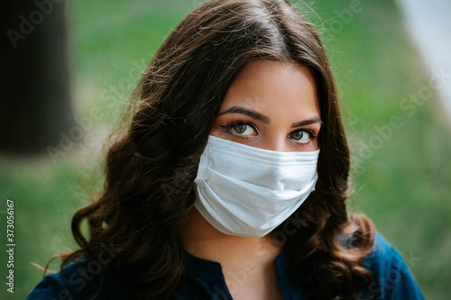 Corona virus lifestyle concept of a young women in city street who walks with surgical or protecting mask during pandemic.