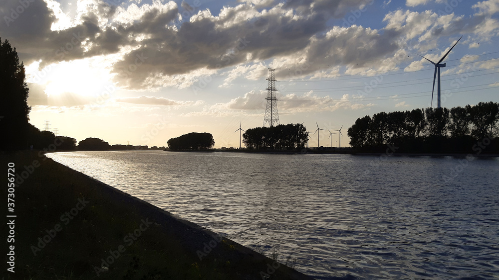 Sunset silhouette on the shore of a canal in industrial area