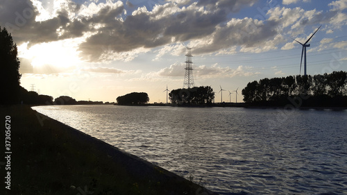 Sunset silhouette on the shore of a canal in industrial area