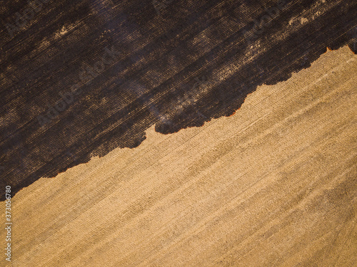 Aerial photography of the burning and scorched dry fields. Dry grass burns in the reserve. Natural disaster. The ground is covered with black ash after the fire. Top view drone shot. Beauty of earth.
