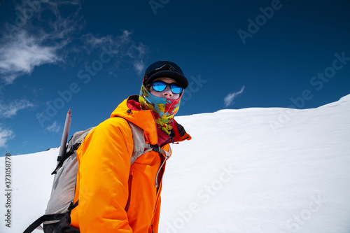 Portrait of a stern climber skier in sunglasses and a cap with a ski mask on his face. against the backdrop of Mount Elbrus