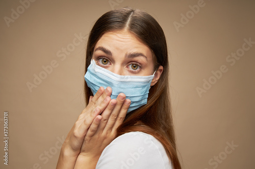 Beautiful woman in medical mask covered her face with her hands and close-up 