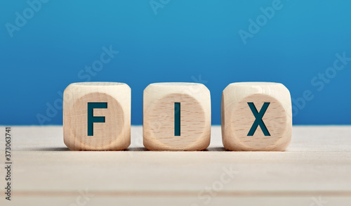 The word fix on wooden cubes with blue background. Fixing, repairing or solution concept.