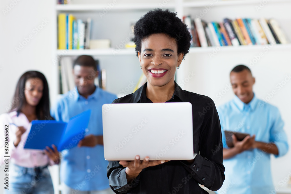 Laughing african american businesswoman at computer with group of black business people Laughing african american businesswoman at computer with group of black business people