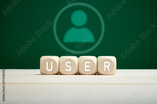 The word user on wooden blocks against a user icon on green background. Technology, communication or internet user concept.