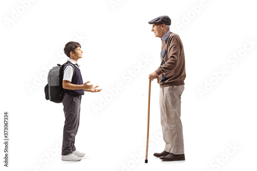 Full length profile shot of a schoolboy and a grandfather having a conversation