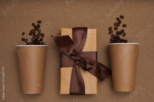 Two craft glasses with gift box and coffee beans on craft background . Monochrome photo